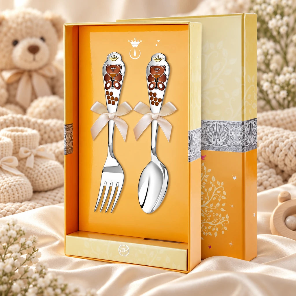 Kinderbesteck Teddybär 925 Silber Honigbär — Emaille braun 2-tlg in der Original-Geschenkbox — Lifestyle-Aufnahme auf cremefarbenem Satin mit Plüschtier und Schleierkraut, Geschenk zur Geburt