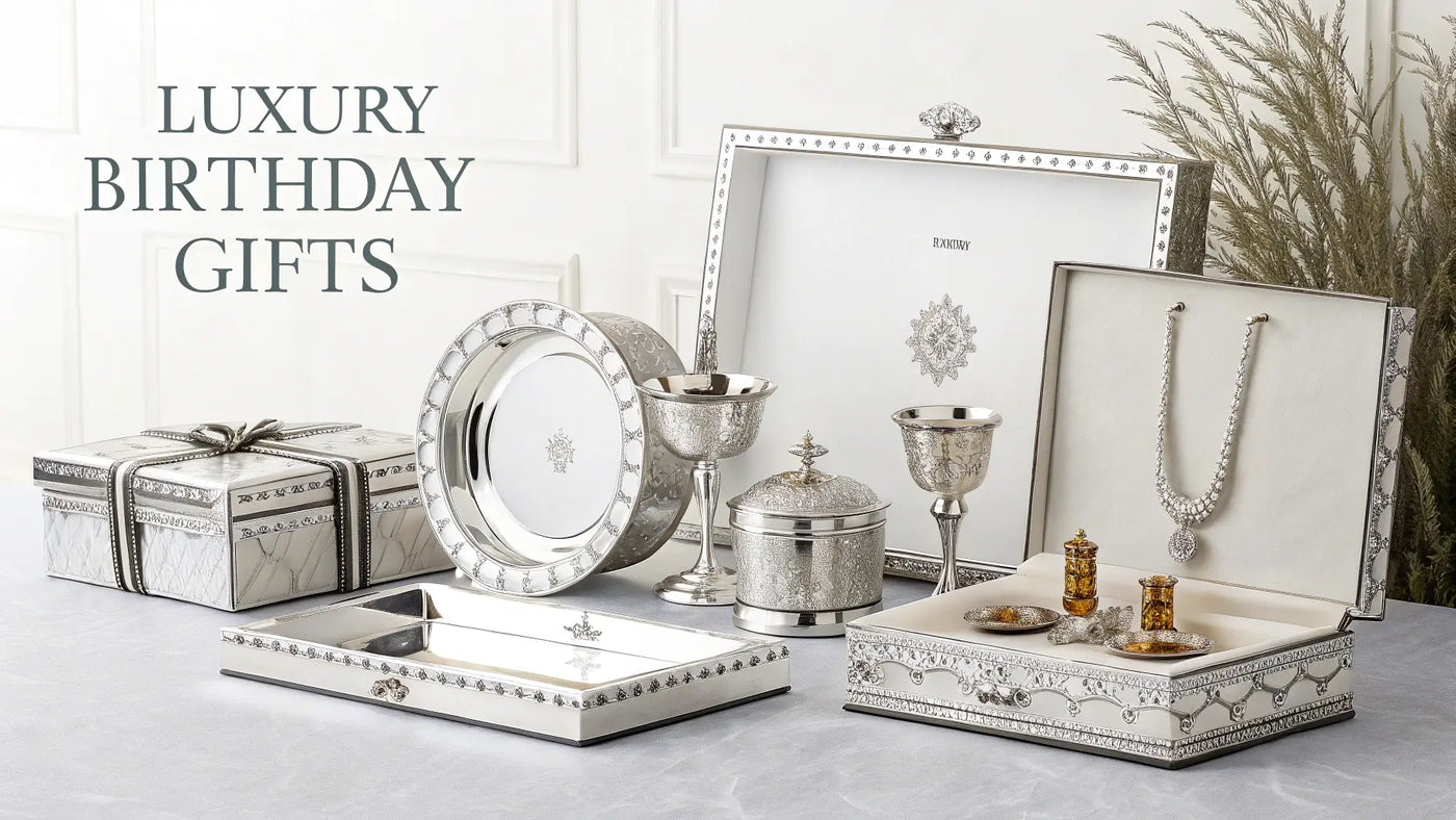Luxuriöse Silbergeschenke zum Geburtstag: Tablett, Kelch, Schmuckset und Geschenkboxen auf edler Tafel stilvoll arrangiert.