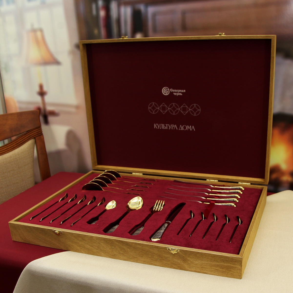 Offener Besteckkoffer schräg von vorn: Esslöffel und Messer liegen, ein Gedeck vollständig, Fächer für Gabeln und Teelöffel leer