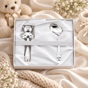 Baby Geschenkset 925 Silber Sitzender Teddy, Stielrassel und Babylöffel in weißer Zaramella-Box, Lifestyle-Aufnahme mit Plüschbär und Schleierkraut
