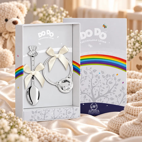 Baby Geschenkset Löffel & Rassel Teddybär in der Original-Geschenkbox — Lifestyle-Aufnahme auf cremefarbenem Satin mit Plüschtier und Schleierkraut, Geschenk zur Geburt