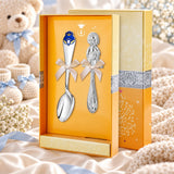 Baby Geschenkset Prinz – Rassel & Kinderlöffel 925 Silber in der Original-Geschenkbox — Lifestyle-Aufnahme auf cremefarbenem Satin mit Plüschtier und Schleierkraut, Geschenk zur Geburt