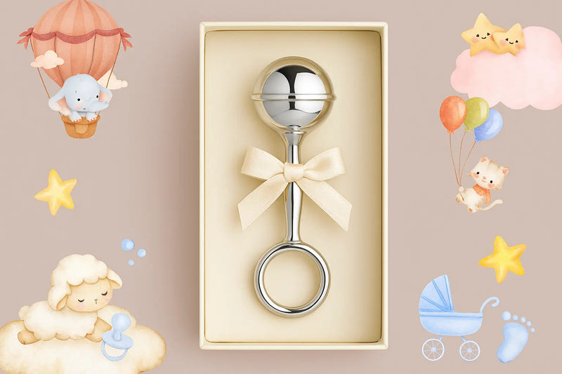 Silberne Babyrassel mit Schleife in Geschenkbox, auf weichem Stoff drapiert – elegantes Geburtsgeschenk in stilvoller Präsentation.