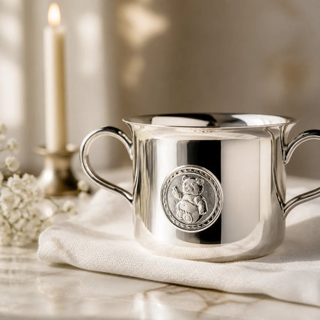 Babytasse 925 Silber Teddybär auf weißem Leinen mit brennender Kerze und Schleierkraut, Detailansicht des Teddybär-Medaillons — Lifestyle