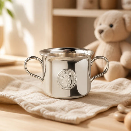 Babytasse 925 Silber Teddybär auf cremefarbener Musselin-Decke im Kinderzimmer, Plüsch-Teddybär im Hintergrund — Lifestyle