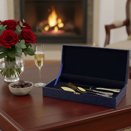 Besteckset 4-teilig vergoldet in Geschenkbox am romantischen Kaminfeuer mit Rosen und Champagner.