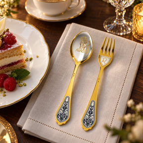 Dessertbesteck Sternzeichen Löwe aus 925 Silber vergoldet neben einem Dessertteller mit Torte – vergoldetes Löwe-Bild im Löffel, Symbol auf der Gabel