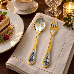 Dessertbesteck Sternzeichen Schütze aus 925 Silber vergoldet neben einem Dessertteller mit Torte – vergoldetes Schütze-Bild im Löffel, Symbol auf der Gabel
