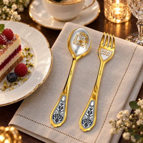 Dessertbesteck Sternzeichen Wassermann aus 925 Silber vergoldet neben einem Dessertteller mit Torte – vergoldetes Wassermann-Bild im Löffel, Symbol auf der Gabel