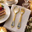 Dessertbesteck Sternzeichen Zwillinge aus 925 Silber vergoldet neben einem Dessertteller mit Torte – vergoldetes Zwillinge-Bild im Löffel, Symbol auf der Gabel