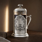 French Press aus 925 Sterling Silber mit Akanthus-Medaillon im warmen Abendlicht auf dunklem Nussholz — Lifestyle