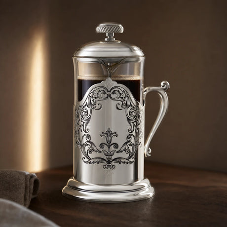 French Press aus 925 Sterling Silber mit Akanthus-Medaillon im warmen Abendlicht auf dunklem Nussholz — Lifestyle