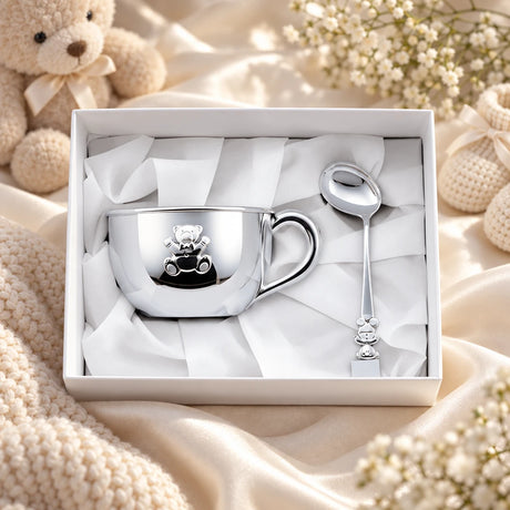 Geschenkset Zaramella Bär 925 Silber — große Tasse + Babylöffel in der Original-Geschenkbox — Lifestyle-Aufnahme auf cremefarbenem Satin mit Plüschtier und Schleierkraut, Geschenk zur Geburt