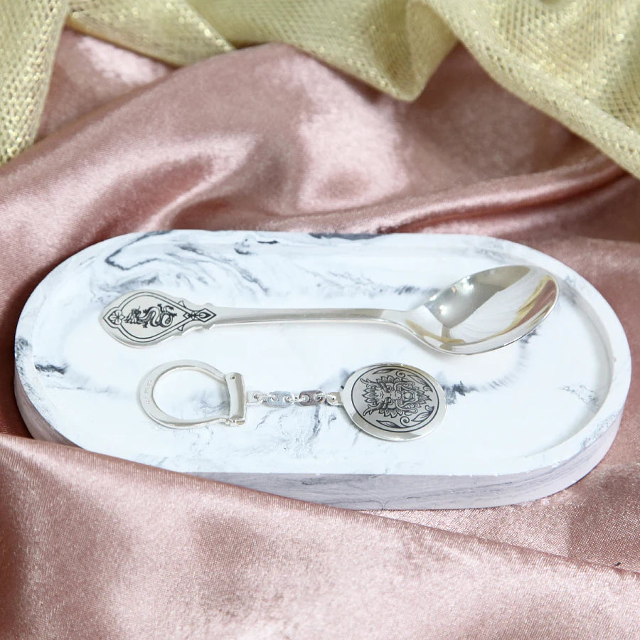 Geschenkset Drache 925 Silber Niello auf Marmor — Lifestyle-Inszenierung mit Schlüsselanhänger und Löffel auf rustikaler Marmoroberfläche, dekorativer Geschenkmoment