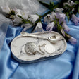 Geschenkset Hilfe des Heilers 925 Silber im offenen Etui — Wasser-Anhänger und Teelöffel auf hellblauem Stoff dekoriert mit weißen Frühlingsblumen, Lifestyle-Ansicht des spirituellen Geschenks von SevChern