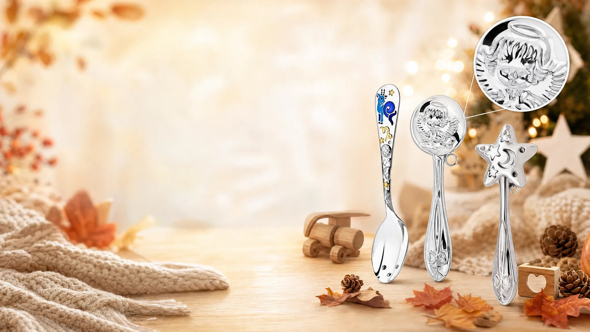 Babygeschenke aus 925 Silber im Herbst: Babylöffel Steinbock, Schutzengel-Rassel und Sternrassel zwischen Herbstlaub und Lichtern