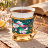 Kaffeetasse aus Porzellan und Silber mit Goldfisch-Emaille-Motiv — Lifestyle-Setting am Teetisch