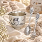 Kinder Set „Eulen“ – Silber mit Niello & Gravur — Lifestyle-Aufnahme auf cremefarbenem Satin mit Plüschtier und Schleierkraut, Geschenk zur Geburt