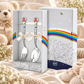 Kinderbesteck Teddybär 925 Silber — Emaille purpur-gold 2-tlg in der Original-Geschenkbox — Lifestyle-Aufnahme auf cremefarbenem Satin mit Plüschtier und Schleierkraut, Geschenk zur Geburt