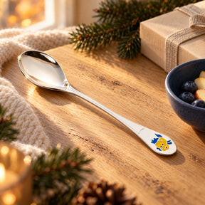 Kinderlöffel 925 Silber mit Emaille-Fisch auf Eichenholz am Fenster, Tannenzweige und Geschenkschachtel im warmen Vorweihnachtslicht — Lifestyle