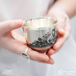 Kindertasse 925 Silber Niello — Kinderhände halten Tasse mit Niello-Mädchenmotiv, Lifestyle-Aufnahme, 125 ml, Taufgeschenk