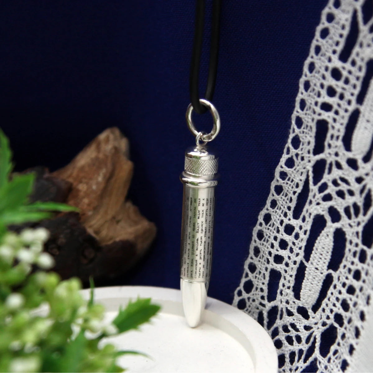 Patrone als Silberanhänger an schwarzem Band — Psalm 91 rundum auf der Hülse, Geschenk für Jäger, vor blauem Stoff und Spitze