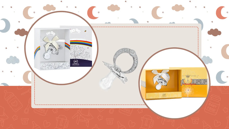 Schnuller aus 925er Silber mit Niello-Verzierung, präsentiert in eleganten Geschenkboxen – edles Geburtsgeschenk mit Symbolkraft und Schleife.