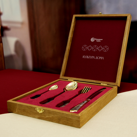 Besteck Zar Saltan in geöffneter Holzschatulle — Teelöffel, Esslöffel, Gabel und Messer, schräg auf rotem Tischtuch