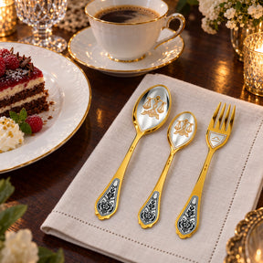 Sternzeichen-Set Waage: drei vergoldete Silberstücke an der Kaffeetafel neben Dessertteller und Tasse