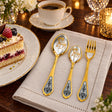 Sternzeichen-Set Widder: drei vergoldete Silberstücke an der Kaffeetafel neben Dessertteller und Tasse