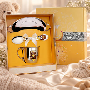 Geschenkset Teddybär 925 Silber Emaille — Tasse, Löffel & Teller in der Original-Geschenkbox — Lifestyle-Aufnahme auf cremefarbenem Satin mit Plüschtier und Schleierkraut, Geschenk zur Geburt