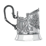 Podstakannik Troika 925 Silber Seitenansicht — klassischer Bügelhenkel mit Perlrand und Akanthus-Voluten, hochglanzpolierter Standfuß, antik patinierte Hochrelief-Szene mit Schlittenfahrt im Schnee