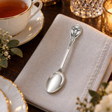 Teelöffel Ziege 925 Silber Niello neben einer Teetasse auf heller Leinenserviette, Ziegenkopf im Medaillon am Stiel