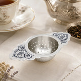 Teesieb 925 Silber mit Niello-Ornament — mit Teetasse, Silberkanne und losem Tee auf Leinentuch drapiert
