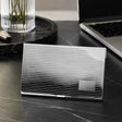 Visitenkartenetui Linea 925 Silber ArgentA — Lifestyle-Aufnahme auf dunklem Marmor-Schreibtisch mit Laptop, Stift und Vase im Hintergrund, Premium-Business-Setting