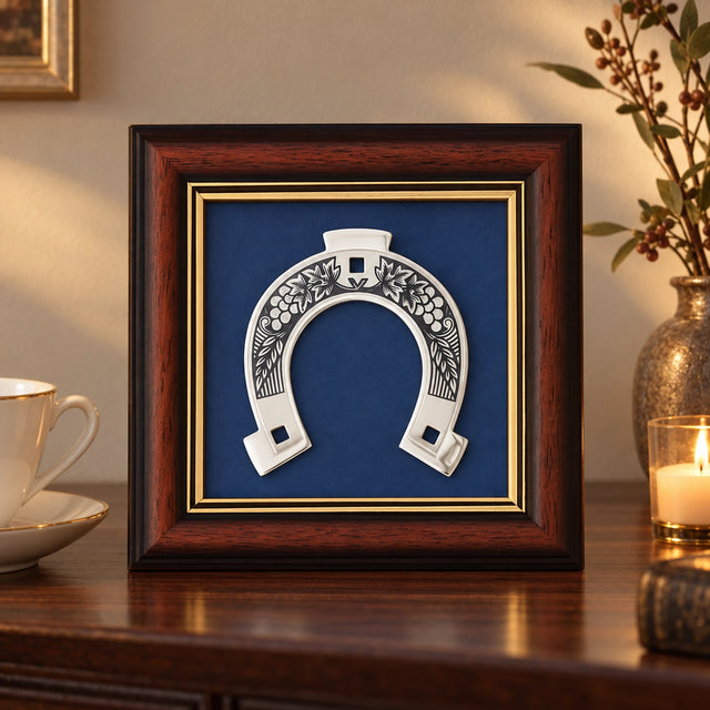 Wandbild Glückshufeisen 925 Silber Niello, 15 × 15 cm, auf einer dunklen Kommode neben einer Teetasse